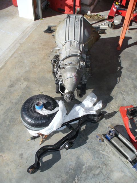 1995 Ford Thunderbird - A disassembled car transmission and torque converter are laid out on a garage floor.