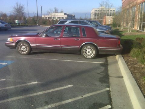 1993 Lincoln Town Car - This maroon 1993 Lincoln Town Car is parked in a lot, showing its side profile.