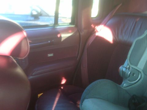 1993 Lincoln Town Car - The interior of a car features maroon upholstery and a child safety seat, with a view of the road through the window.