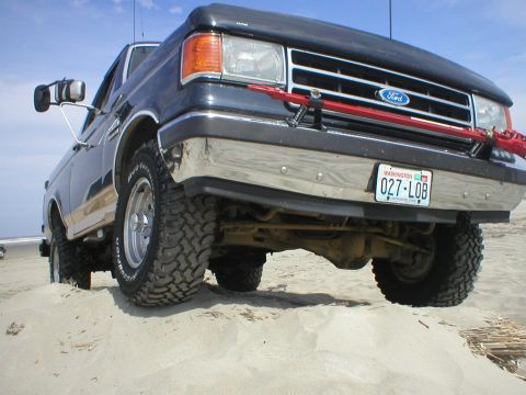 1978 Ford Bronco - This Ford truck, likely from the late 1980s or early 1990s, navigates a sandy terrain with its distinctive grille and off-road tires.
