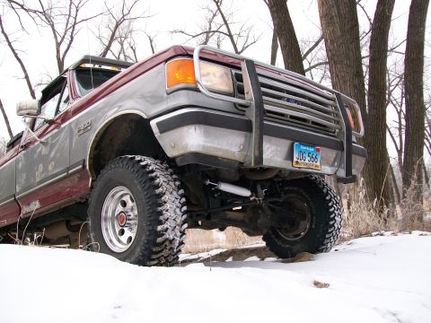 1988 Ford F-150 - A lifted Ford F-Series truck sits in a snowy landscape with trees in the background.