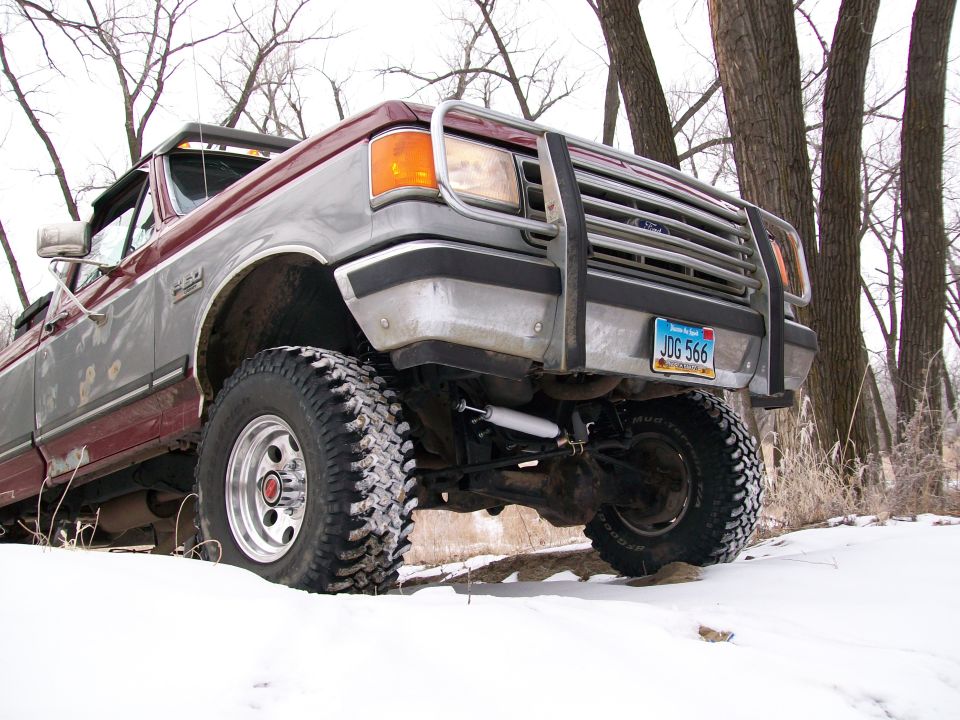Ford F-Series truck with aftermarket grille guard and lift kit in the snow
