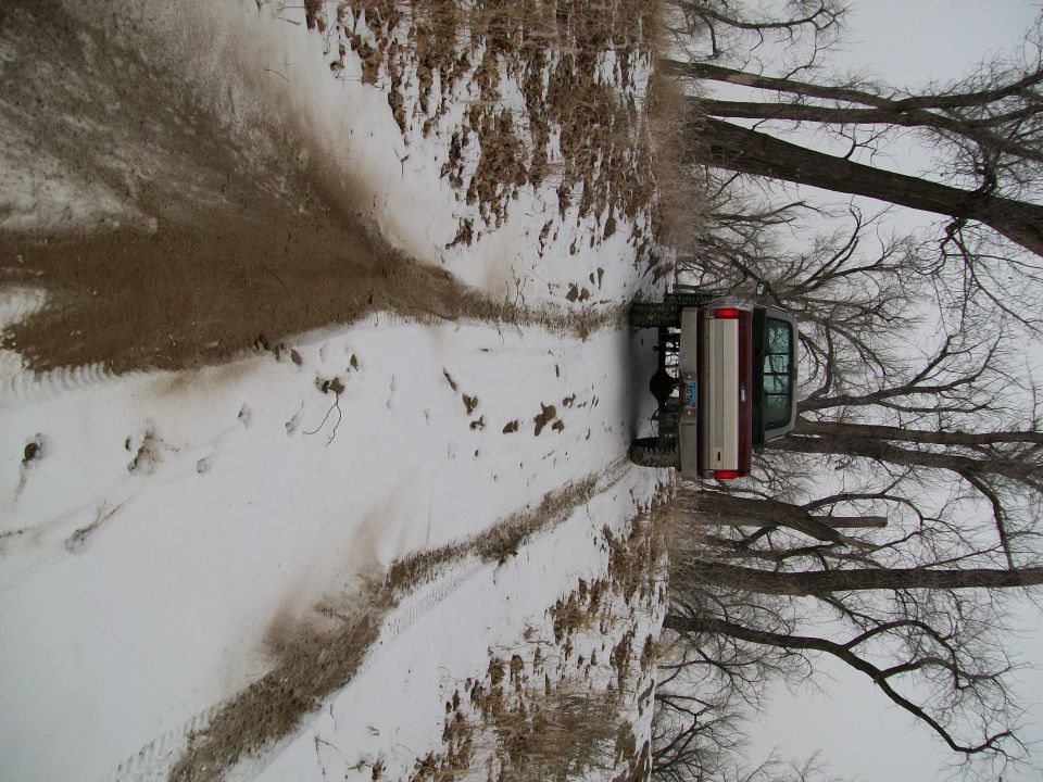 Red and tan pickup truck driving on a snowy dirt road