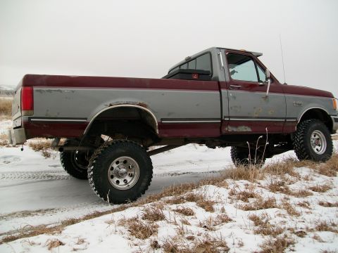 1988 Ford F-150 - Side view of a lifted 1988 Ford F-150 pickup truck in a snowy, rural setting.