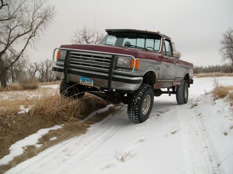 1988 Ford F-150 - This lifted Ford F-150 navigates a snowy path with its front tires off the road.