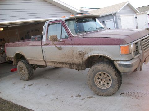 1988 Ford F-150 - This muddy, two-tone pickup truck is likely a 1987 Ford F-150, based on its body style.