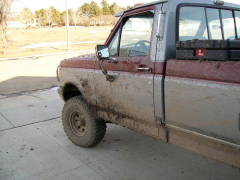1988 Ford F-150 - Mud-covered Ford F-150 pickup truck with visible toolboxes in the bed, seen from the driver's side front quarter angle.