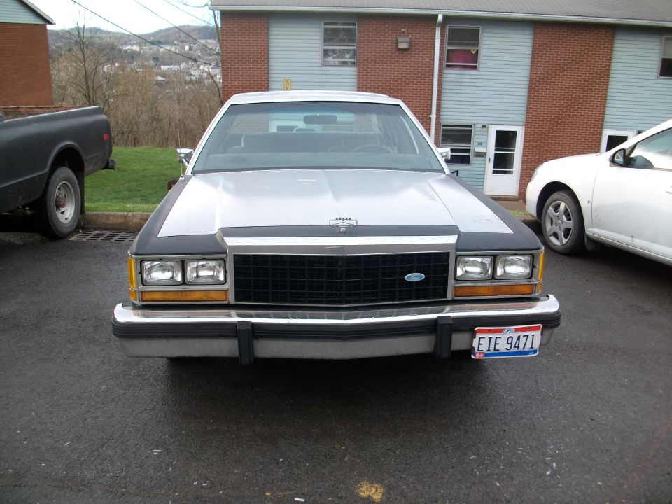 Front view of white Ford LTD Crown Victoria with Ohio plate EIE 9471, parked outside a brick apartment building