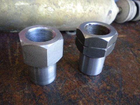 1989 Ford Bronco - Close-up of two threaded metal nuts, with a portion of a cylinder visible in the background.