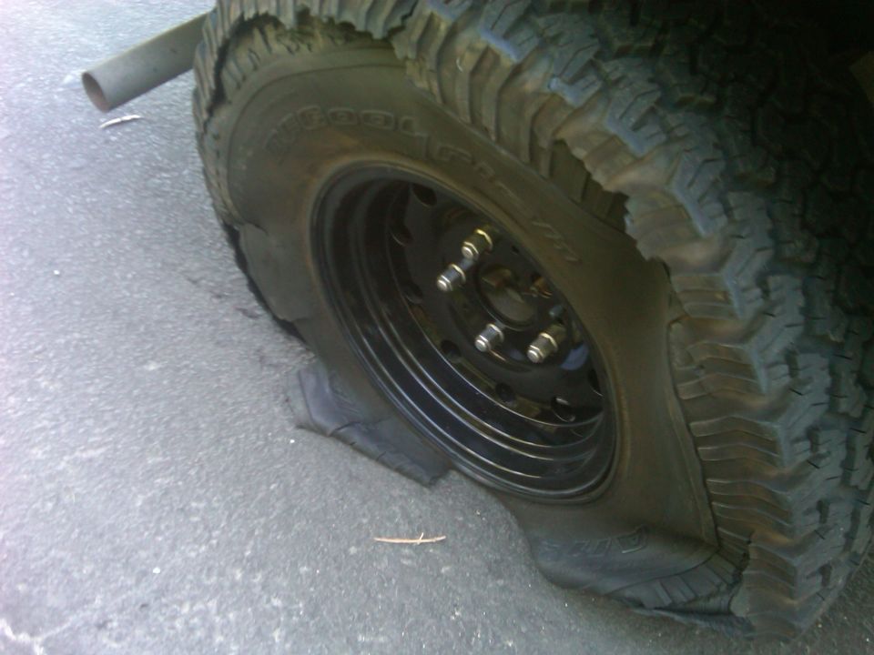 Flat tire on a vehicle, showing the rim and sidewall damage