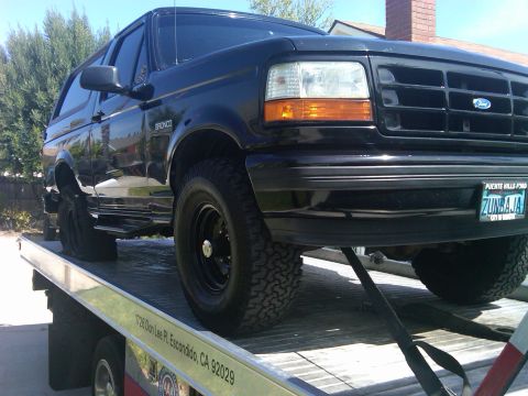 1986 Ford Bronco - This black Ford Bronco, likely from the 1992-1996 generation, is being transported on a tow truck.