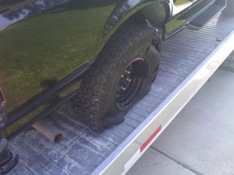 1986 Ford Bronco - Flat tire on a vehicle being loaded onto a trailer.