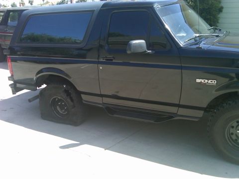 1986 Ford Bronco - This black Bronco has a flat tire on the rear passenger side.
