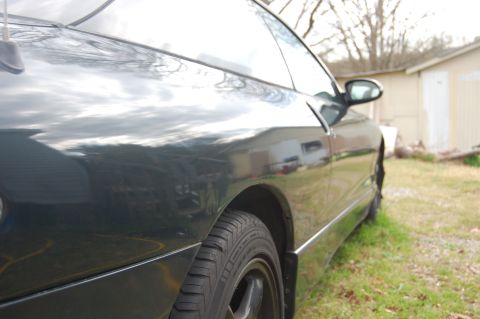 1996 Ford Probe - Side view of a dark green coupe, highlighting the rear wheel and the reflections on its body panels.