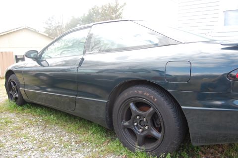 1996 Ford Probe - Side view of a dark green 1996 Ford Probe coupe parked outdoors.