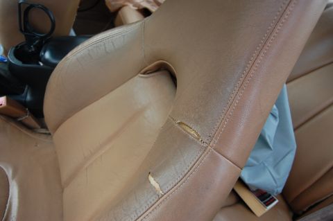 1996 Ford Probe - Close-up of worn tan leather car seats with visible damage and stitching details.