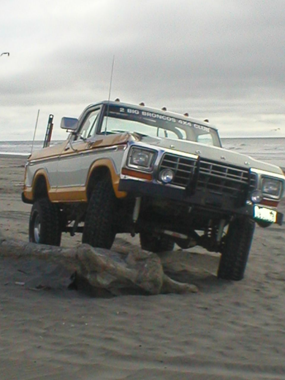 1978 Ford Bronco with "2 BIG BRONCOS 4X4 CLUB" banner on beach, front 3/4 view