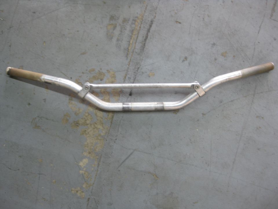 Aluminum handlebars with a crossbar, resting on a concrete floor