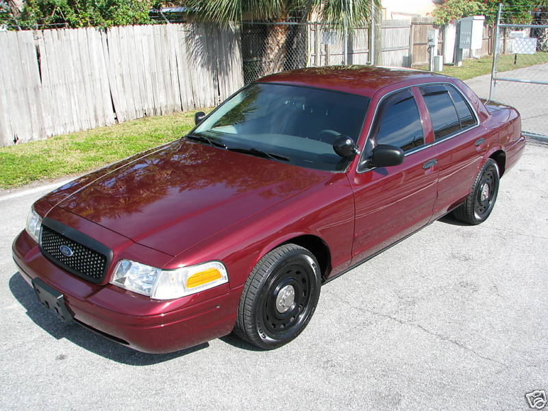 Maroon Ford Crown Victoria with black grille and steel wheels, parked on asphalt