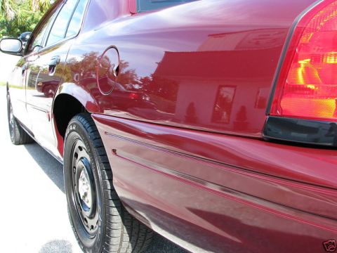 2005 Ford Crown Victoria - Rear quarter panel of a red 2005 Ford Crown Victoria, showing its side profile and taillight detail.