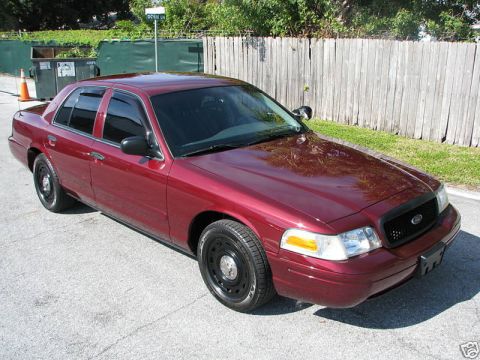 2005 Ford Crown Victoria - Dark red 2005 Ford Crown Victoria with black steel wheels and tinted windows parked outside.