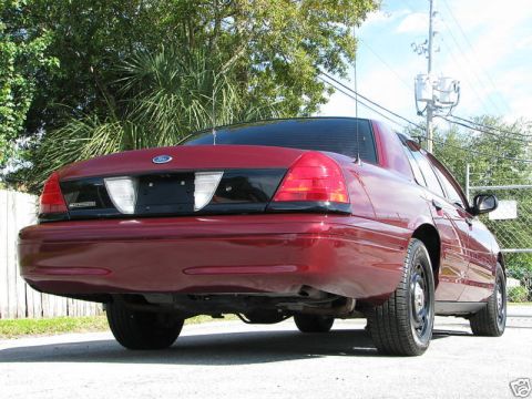 2005 Ford Crown Victoria - Rear quarter view of a red 2005 Ford Crown Victoria, a black panel between the taillights.