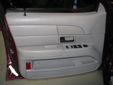 2005 Ford Crown Victoria - The interior door panel shows power window controls and a red reflector on the lower edge.