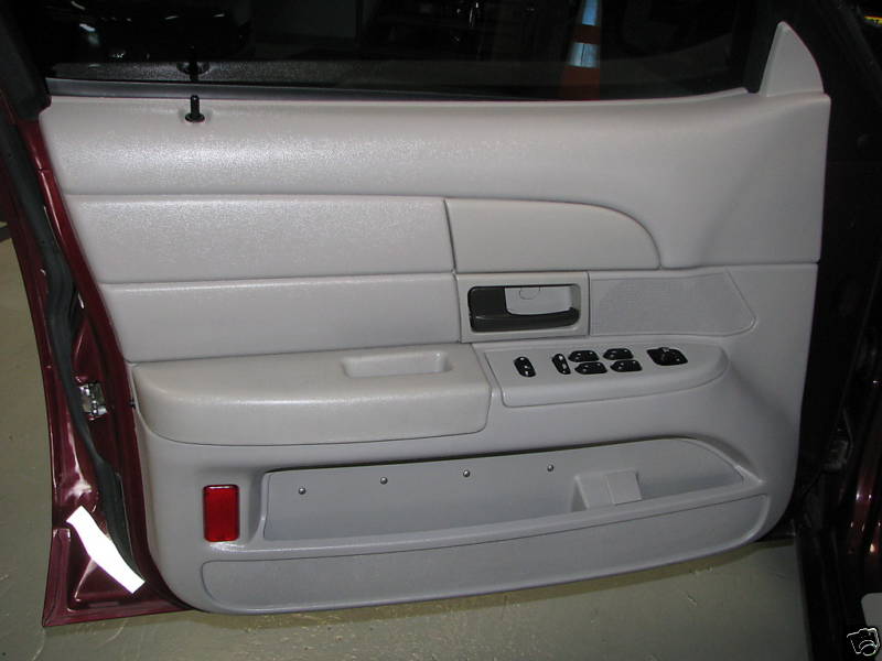 close-up of car's front passenger door panel, light gray with power window controls