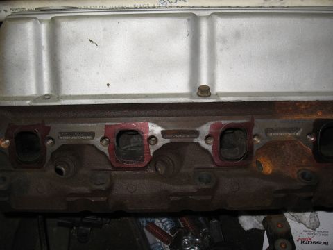 1994 Ford Bronco - Close-up view of an engine cylinder head, showing exhaust ports prepared for gasket installation.