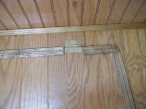 1981 Ford E350 - Interior view of wood paneling and a brass door hinge, likely from a van or RV.