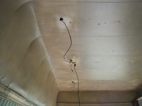 1981 Ford E350 - The interior ceiling of a vehicle shows exposed wiring and some damage to the paneling.