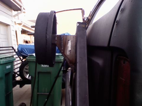 1979 Ford Bronco - This custom-fabricated spare tire carrier mount is attached to the rear of a vehicle, with trash bins visible nearby.