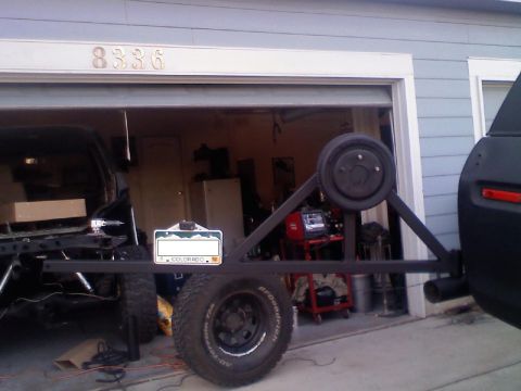1979 Ford Bronco - A rear tire carrier assembly is attached to a black vehicle, with a spare tire and a Colorado license plate visible.
