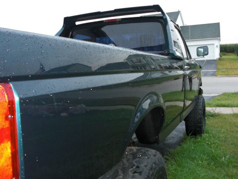 1995 Ford F-150 - Rear view of a dark green 1995 Ford F-150 pickup truck with a spoiler on the cab.