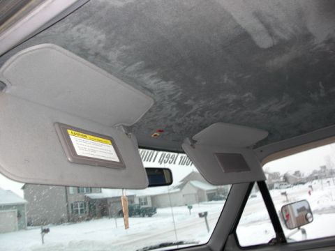 1995 Ford F-150 - The interior of a truck shows the headliner and sun visors, with a snowy residential street visible through the windshield.
