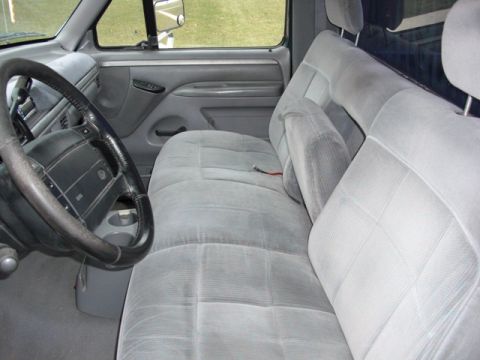 1995 Ford F-150 - Interior view of a truck's gray cloth seats and dashboard, showing the steering wheel and door panel.