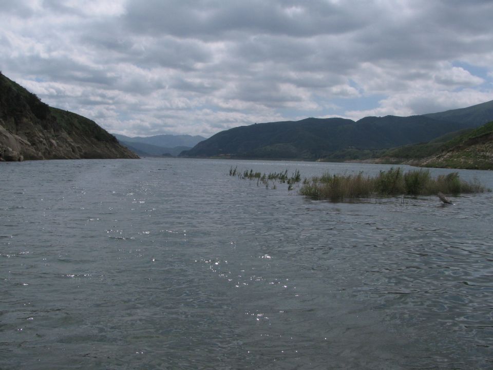 Lake with choppy water, distant hills, and a small island with vegetation