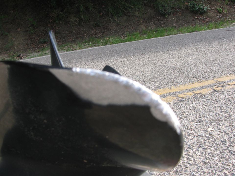 Close-up of a boat's stern with a fin. Road and grassy embankment in background