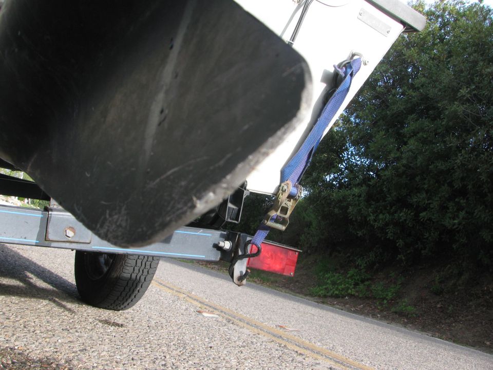 Low angle of boat transom on galvanized trailer with blue ratchet strap and red tail light