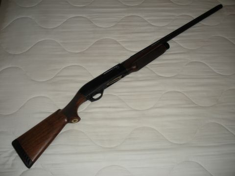 2005 Ford F-250 - A shotgun with a wooden stock and black barrel is displayed on a white quilted surface.