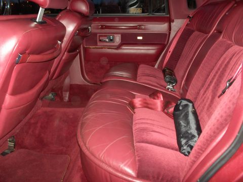 1993 Lincoln Town Car - The interior of a car features red velour and leather seats with red seatbelts.