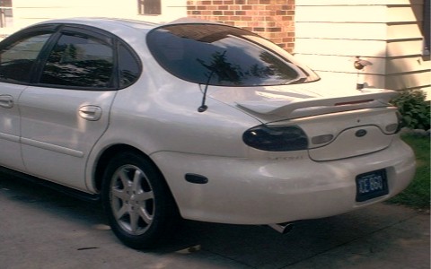 1997 Ford Taurus - Rear view of a white 1997 Ford Taurus sedan with a spoiler and tinted taillights.