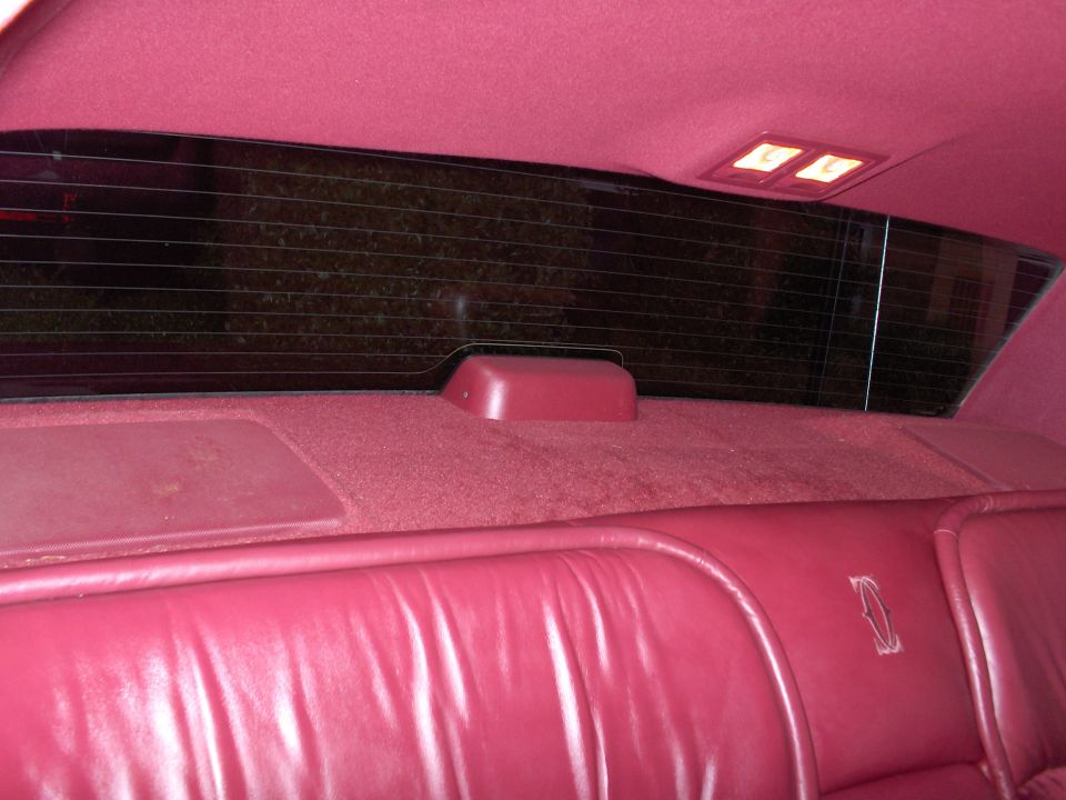 Red leather interior of a 1993 Lincoln Town Car, showing the rear seat and window