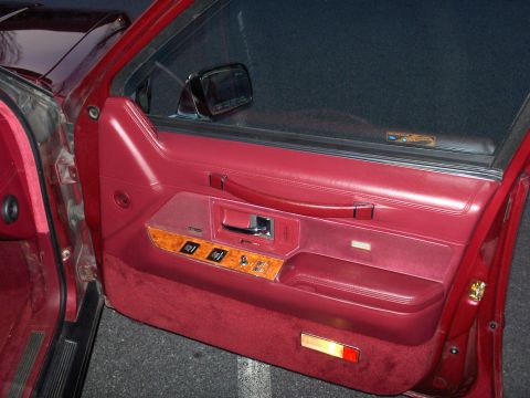 1993 Lincoln Town Car - Close-up of a car's interior door panel, showing red upholstery and wood accents.