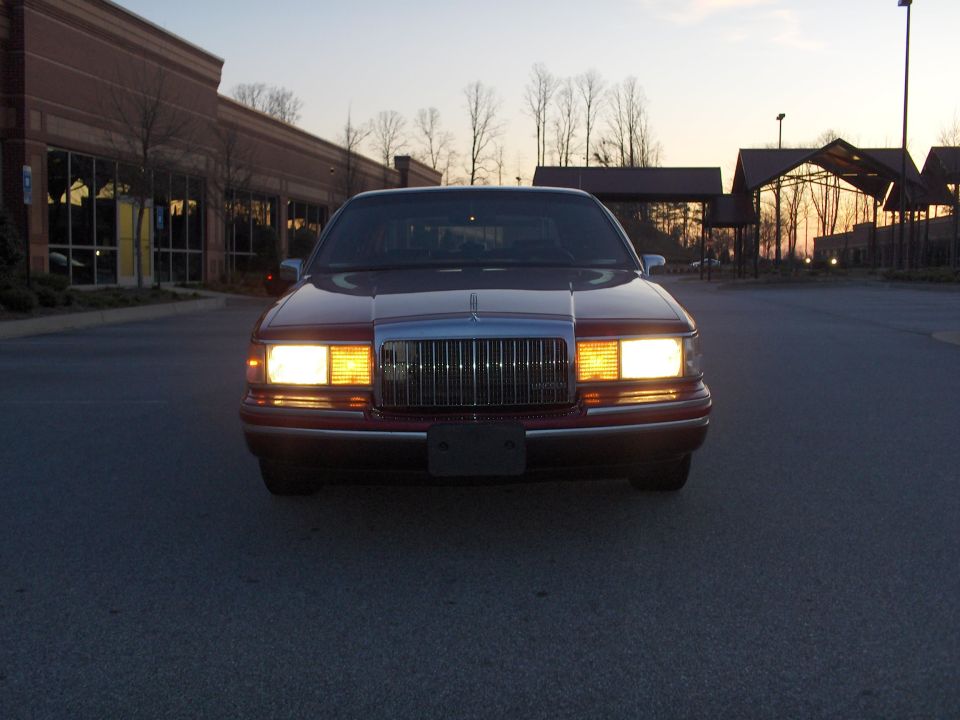 Front view of a 1993 Lincoln Town Car parked outside a building at dusk