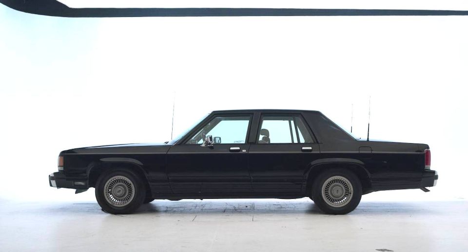 Black sedan, side view. Appears to be a 1980s Ford LTD or similar