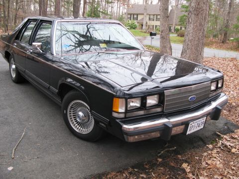 1971 Ford Ranchero - This black sedan features a prominent chrome grille and distinctive wire wheels, suggesting a model from the early 1980s.
