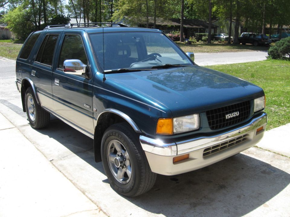Dark teal Isuzu Rodeo SUV, front 3/4 view parked on a driveway