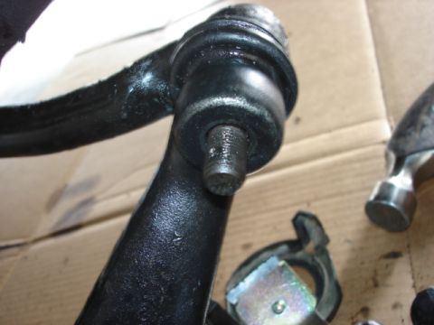 1992 Ford Bronco - Close-up of a black metal automotive ball joint with a threaded stud, resting on a workbench.