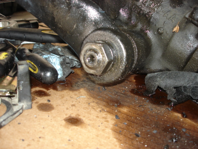Greasy mechanical part with a large bolt and oil stains on wood